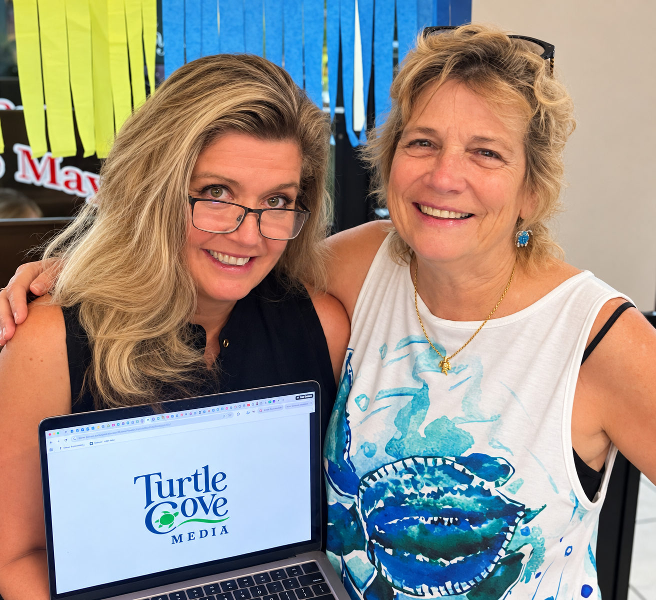 New owner Mandi Broadfoot and founder M.R. Street celebrate the transition to Turtle Cove Media.